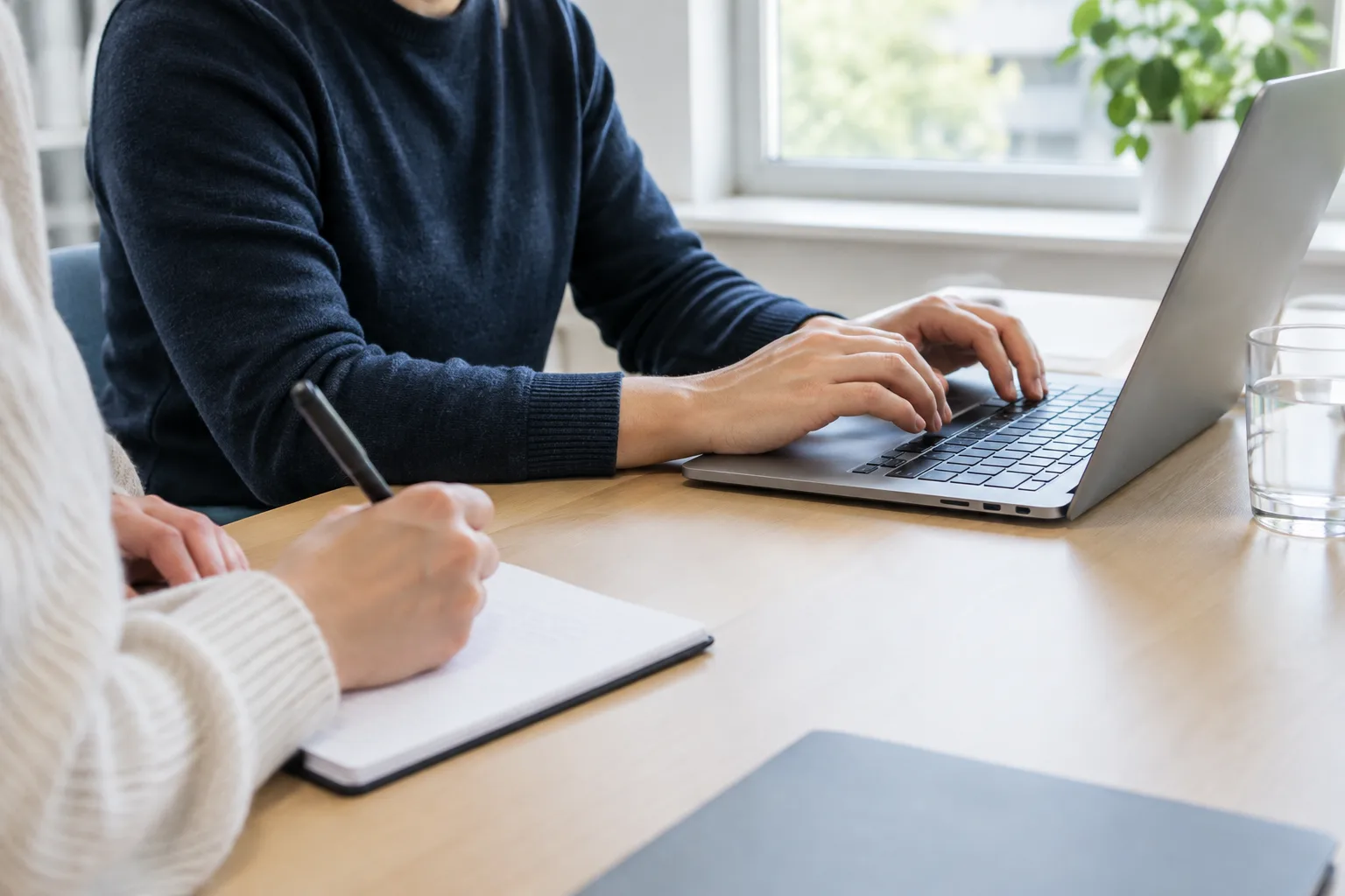 Une personne teste une démarche sur ordinateur tandis qu’une autre prend des notes.