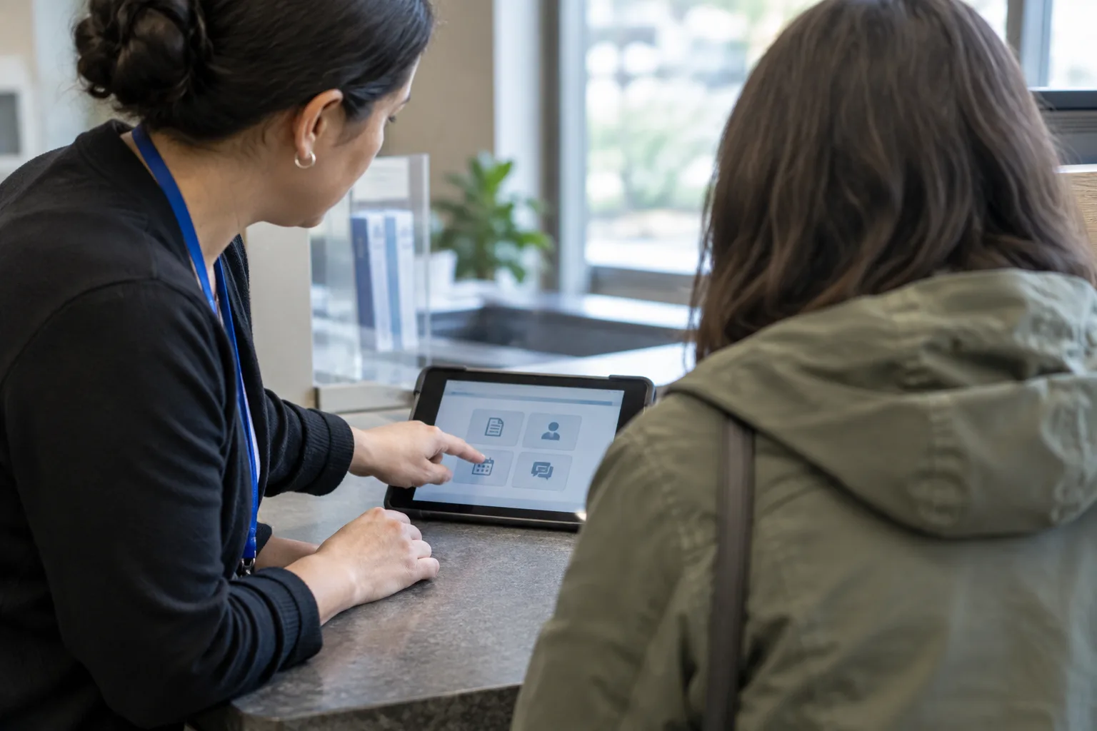 Un agent montre une étape sur une tablette à un usager au guichet.