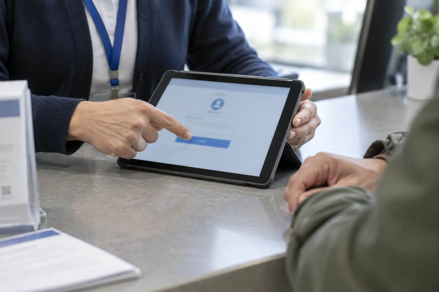 Un agent accompagne un usager devant une tablette au comptoir d’un service public.